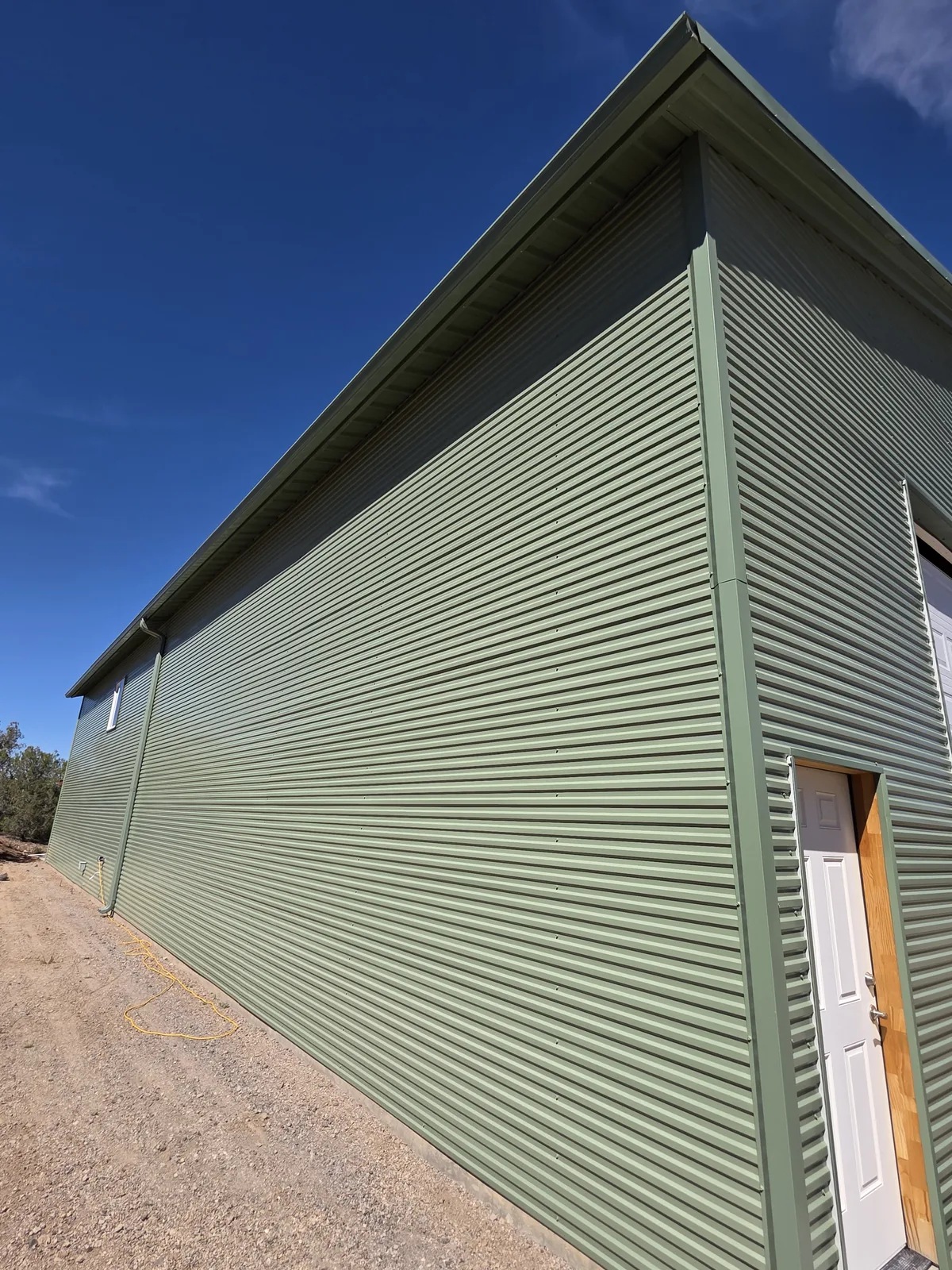 Galvanized steel seamless gutter and downspout on a green metal building in Seligman, AZ