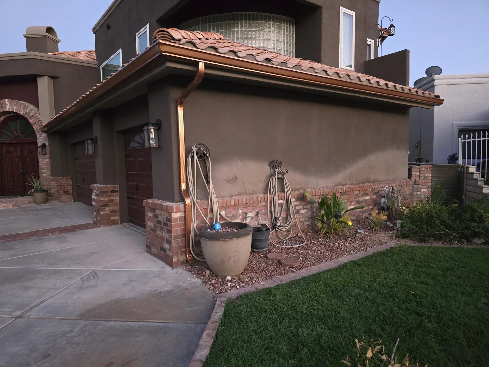 Copper downspout running down a brown stucco and brick home corner in Laughlin, NV