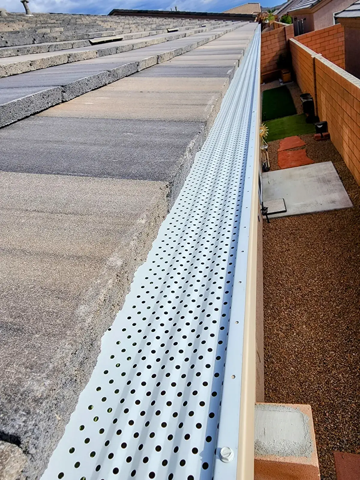 White perforated gutter guard running along a concrete-tile roof in Bullhead City, AZ