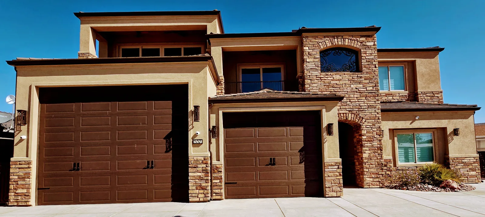 Seamless gutters and downspouts on a two-story stucco and stone home in Mohave Valley, AZ