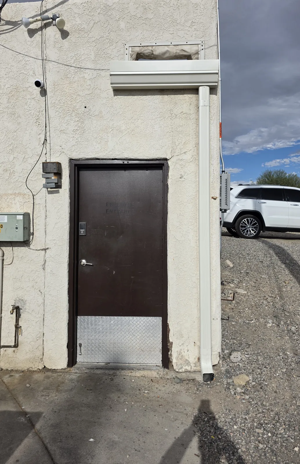 Clean new white gutter and downspout on the same commercial building entrance in Las Vegas, NV after repair