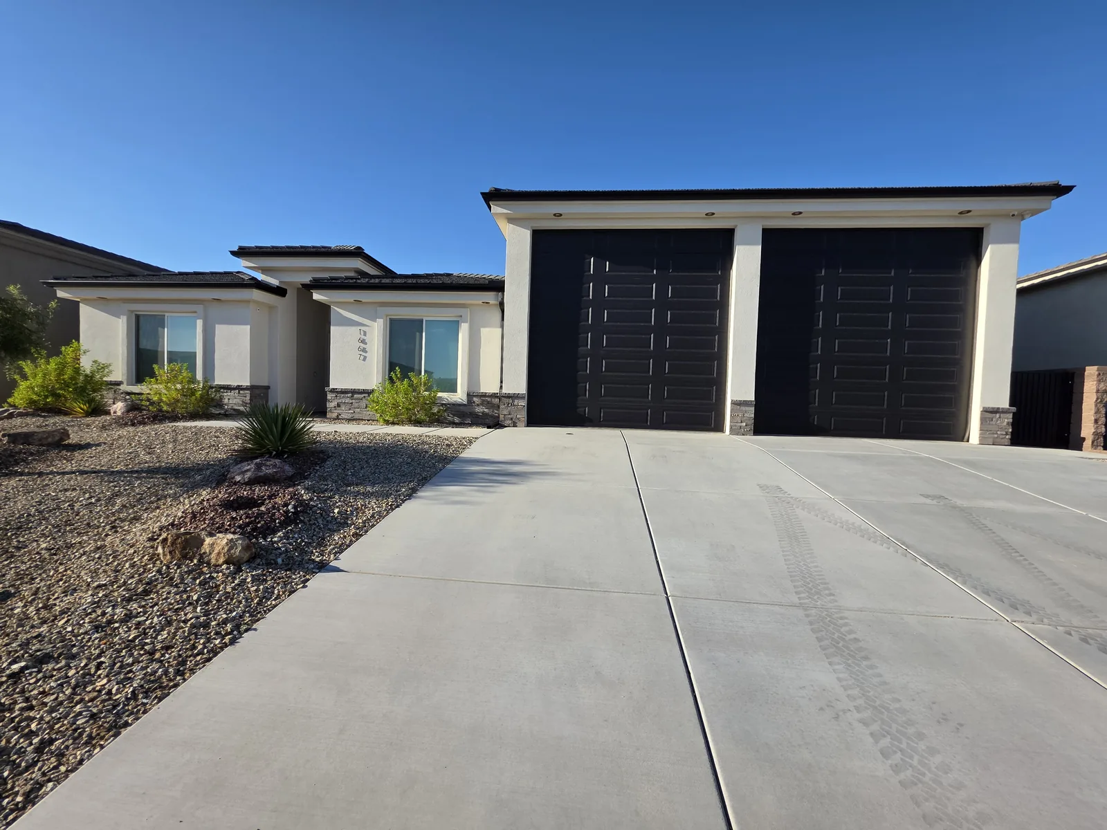 Dark fascia seamless aluminum gutter on a white modern home with black garage doors in Lake Havasu City, AZ
