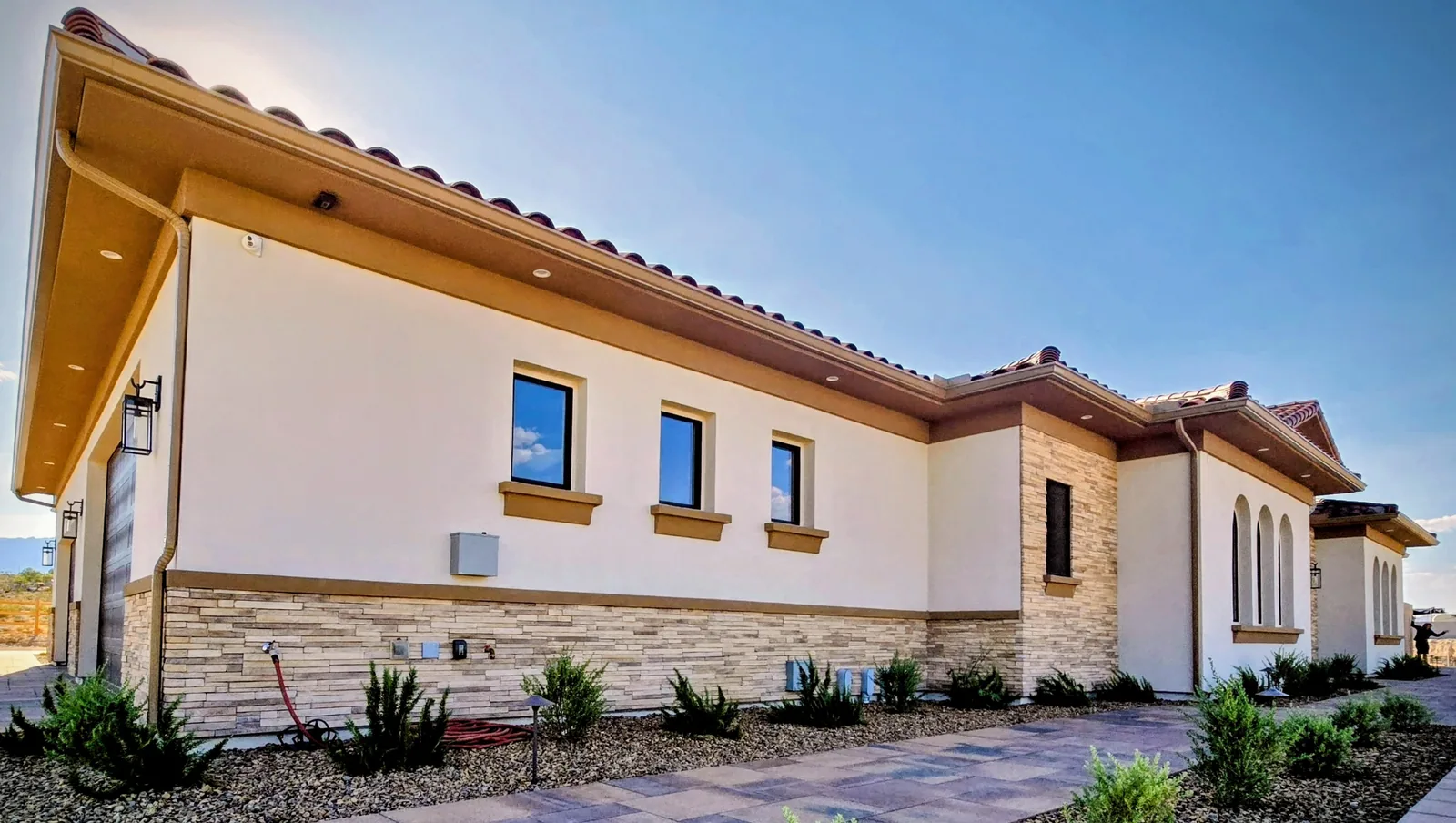 Tan seamless aluminum gutter and downspout on a stone-and-stucco home at golden hour in Las Vegas, NV