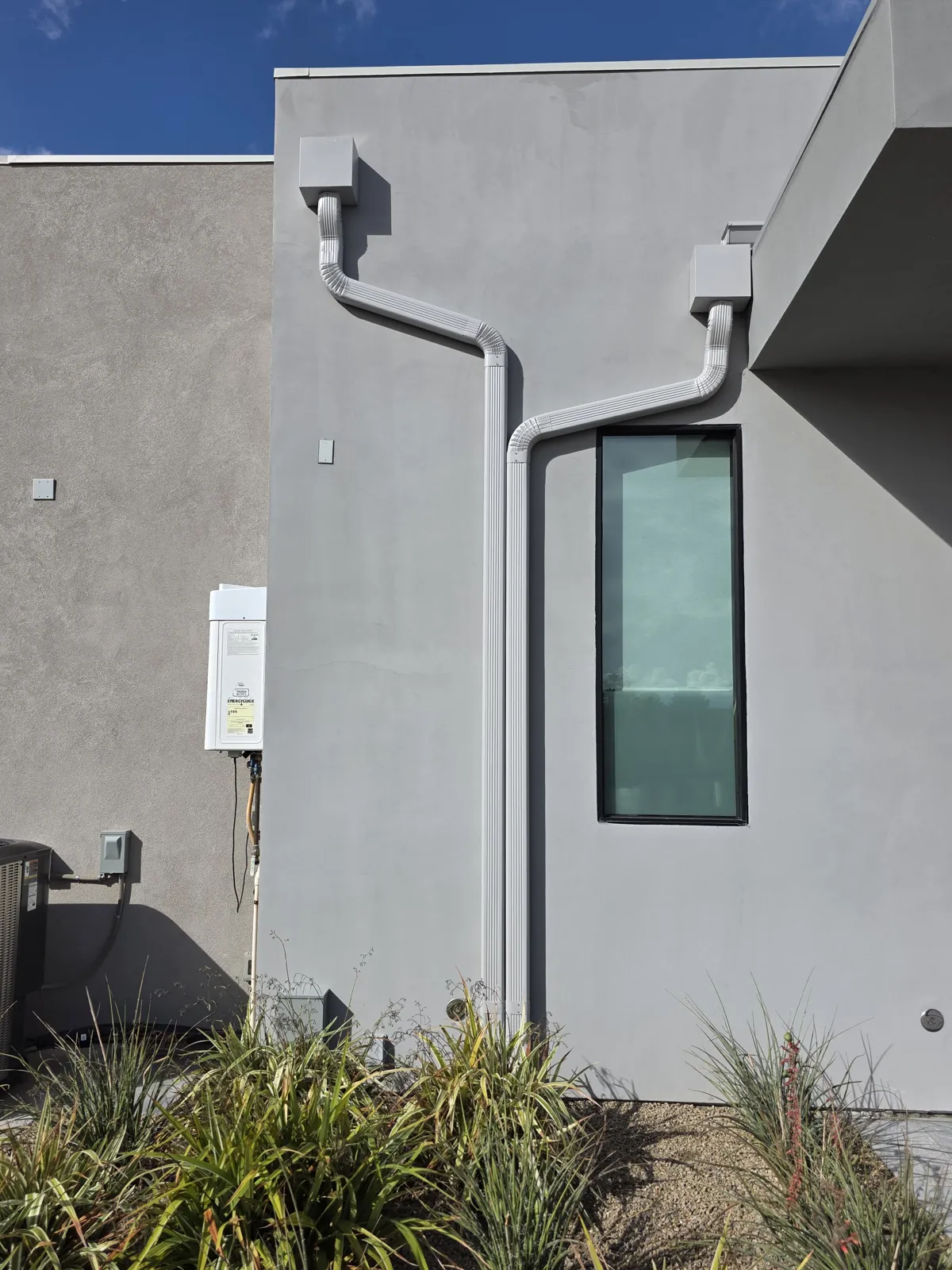 Two box leaderheads feeding offset downspouts on a modern gray stucco home in Las Vegas, NV
