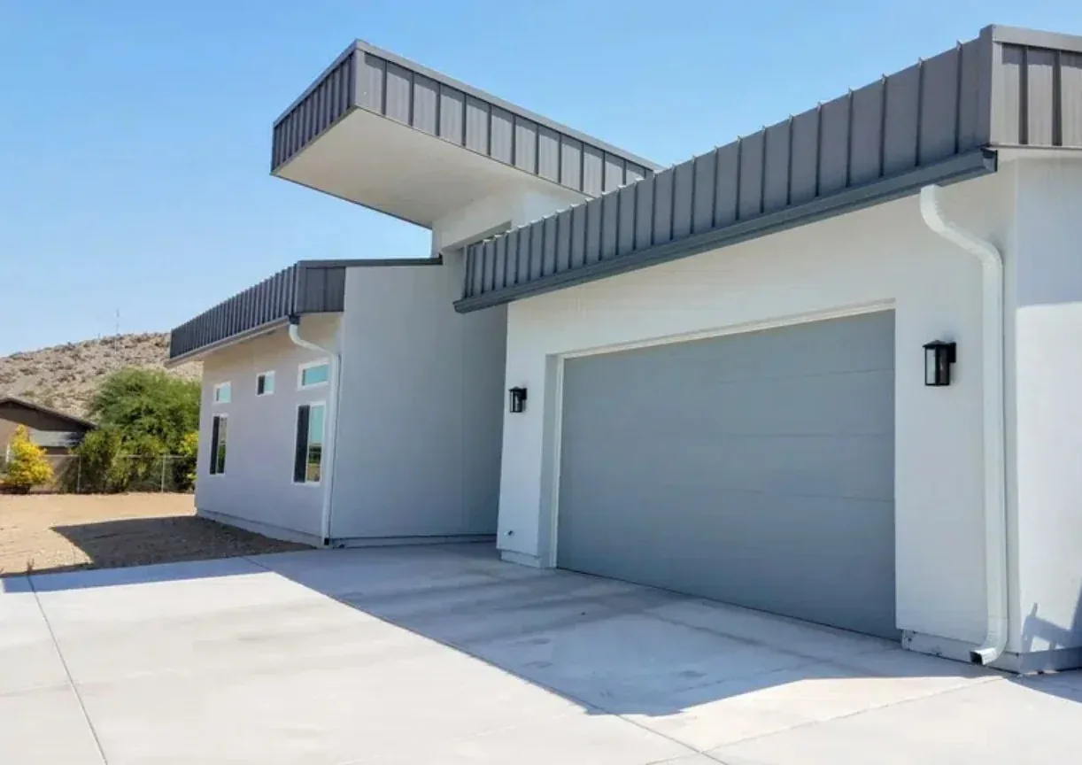 White seamless gutter and downspout system installed on a modern home with clean roofline drainage