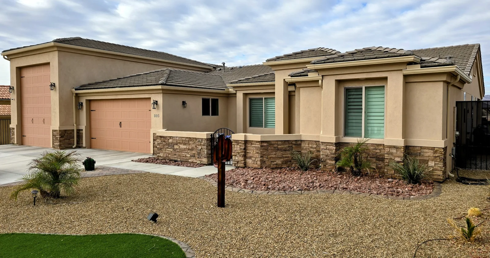 Beige seamless aluminum gutters on a single-story tan stucco home with stone accents and tile roof in Bullhead City, AZ