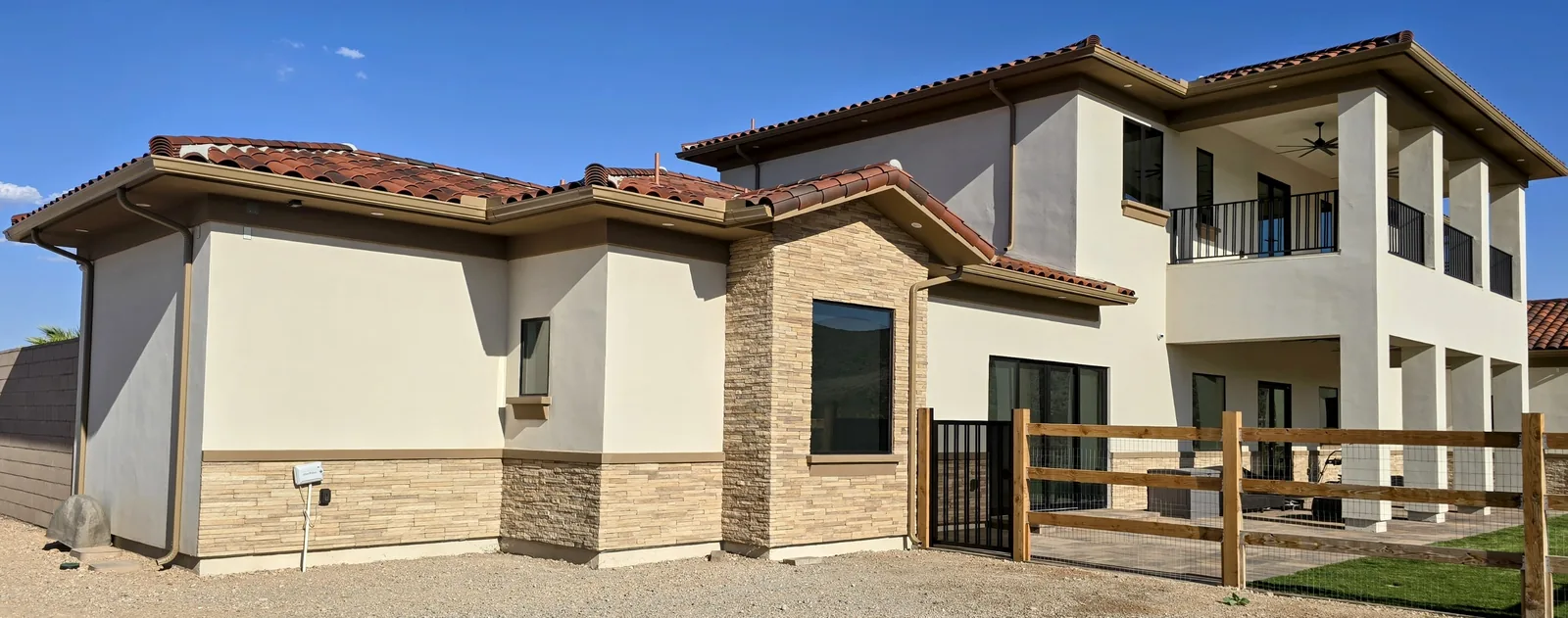 Copper-tone aluminum seamless gutters and downspouts on a two-story Tuscan tile-roof home with stone accents in Las Vegas, NV